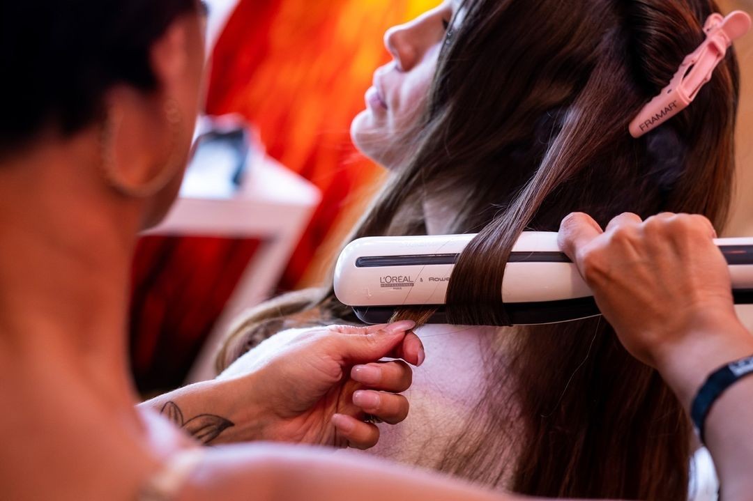 hairstylist styling hair with steam flat iron
